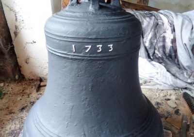 A cast iron bell with the date 1733 embossed and picked out in white numbers.